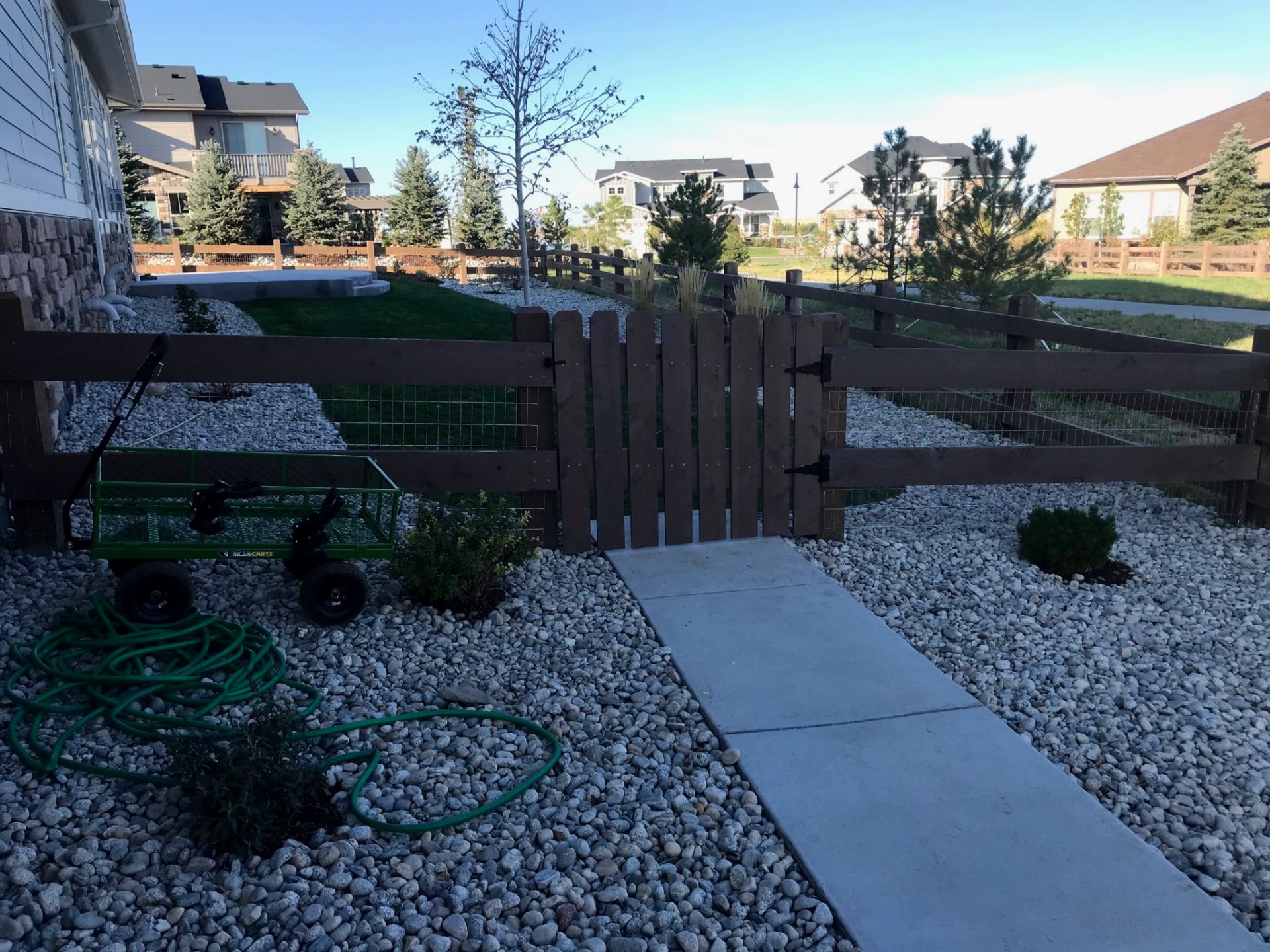 Stained cedar picket gate with split-rail fence and wire mesh
