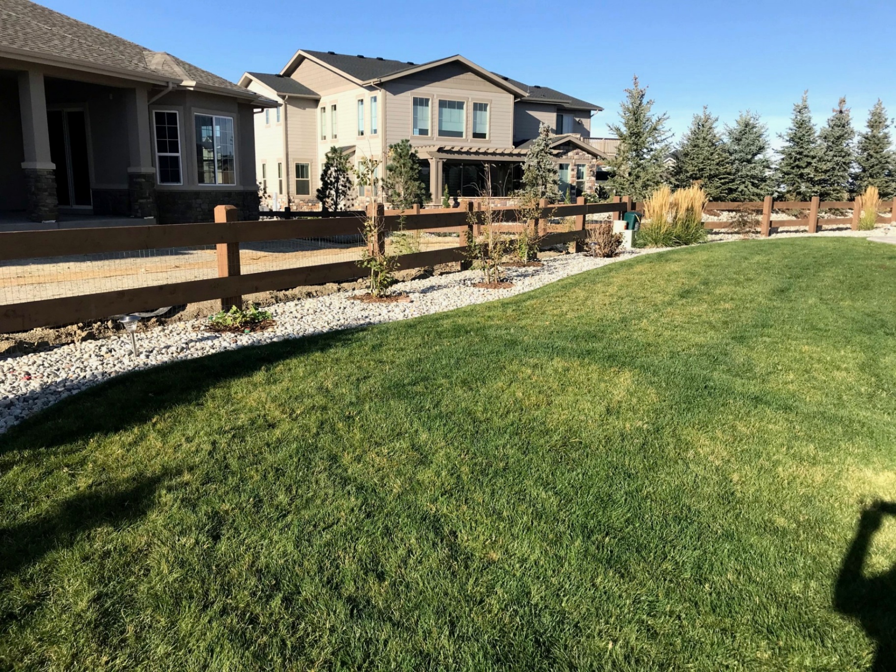 Stained cedar split-rail fence line along finished landscaping
