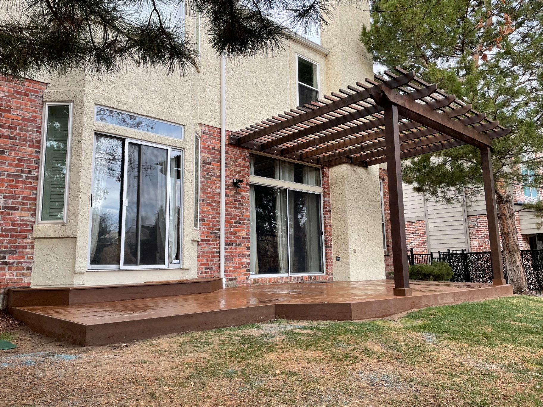 Side view of stained pergola attached to brick home